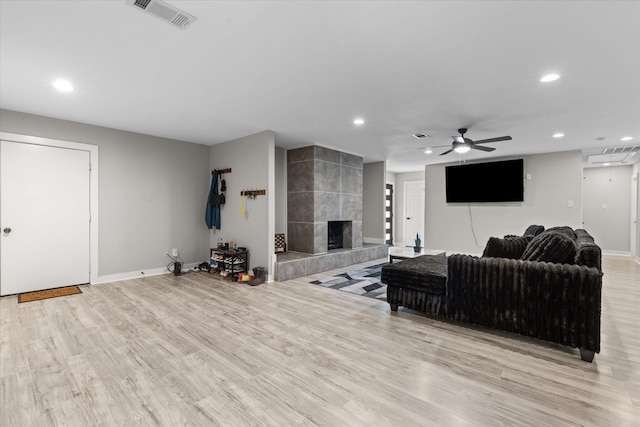 living area featuring baseboards, a ceiling fan, wood finished floors, recessed lighting, and a tiled fireplace