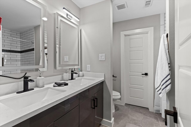 full bath featuring toilet, a tile shower, double vanity, and baseboards