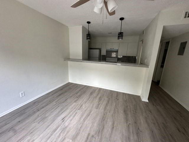 unfurnished living room featuring a ceiling fan, baseboards, wood finished floors, and a textured ceiling
