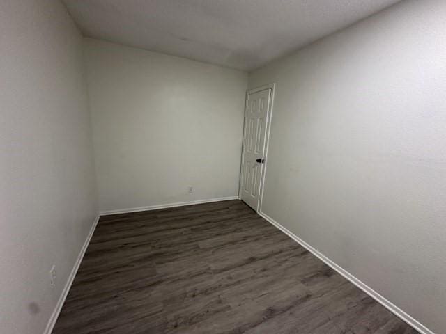 empty room with baseboards and dark wood finished floors