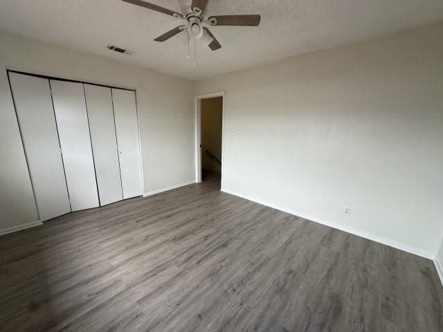 unfurnished bedroom featuring baseboards, visible vents, wood finished floors, and a closet