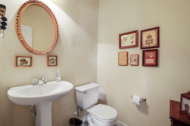 half bath featuring baseboards and toilet