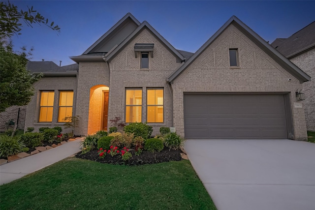 view of front of property with an attached garage, driveway, and brick siding