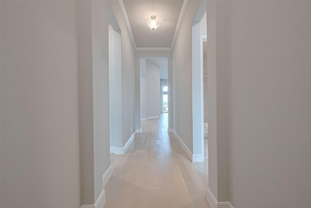 hall featuring light wood-style floors, baseboards, and crown molding
