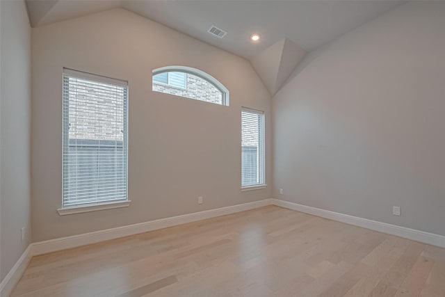 empty room with baseboards, vaulted ceiling, visible vents, and light wood-style floors