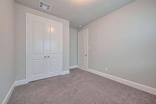 unfurnished bedroom with a closet, baseboards, carpet flooring, and visible vents