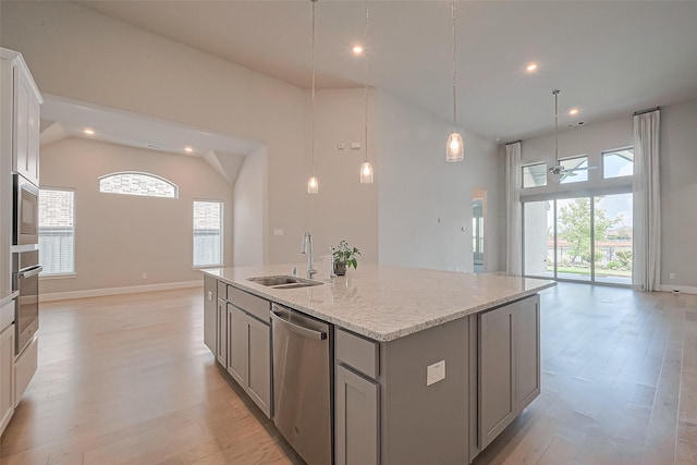 kitchen featuring a sink, light wood-style flooring, stainless steel appliances, open floor plan, and gray cabinetry