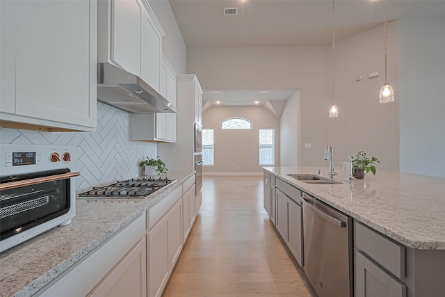 kitchen featuring visible vents, under cabinet range hood, tasteful backsplash, a sink, and stainless steel appliances