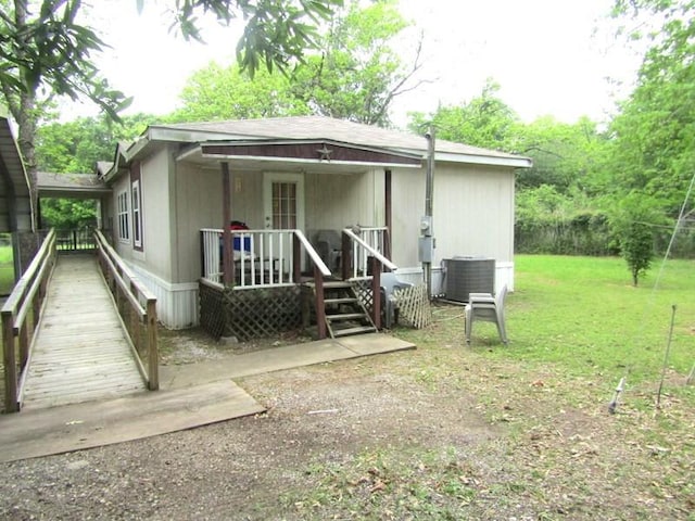rear view of property with central air condition unit, covered porch, and a lawn