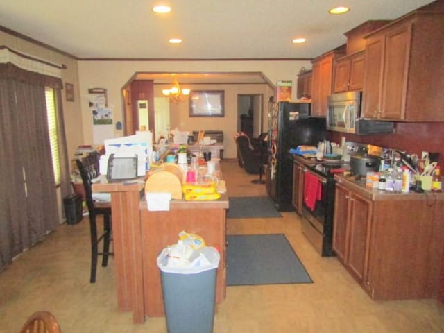 kitchen with arched walkways, a kitchen breakfast bar, a chandelier, brown cabinetry, and stainless steel appliances