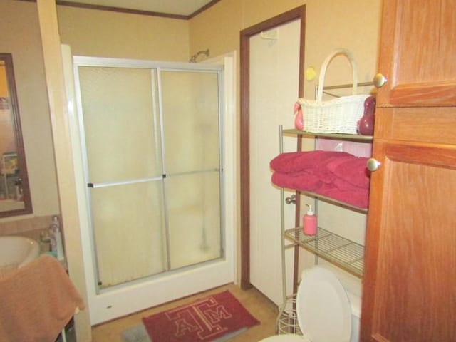 full bath featuring crown molding, toilet, and a shower stall