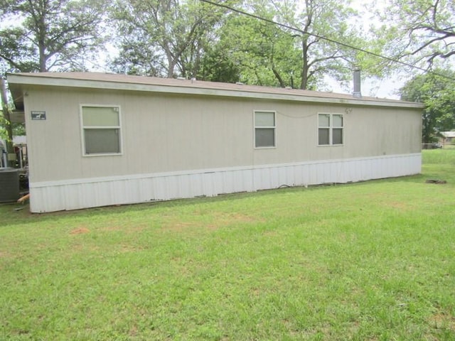 view of side of property with central AC unit and a yard