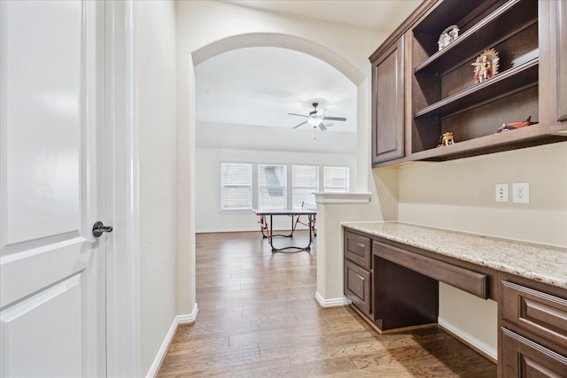 interior space featuring light wood-style floors, arched walkways, and baseboards
