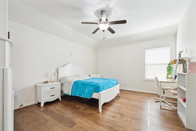 bedroom featuring baseboards, vaulted ceiling, and light wood-style floors