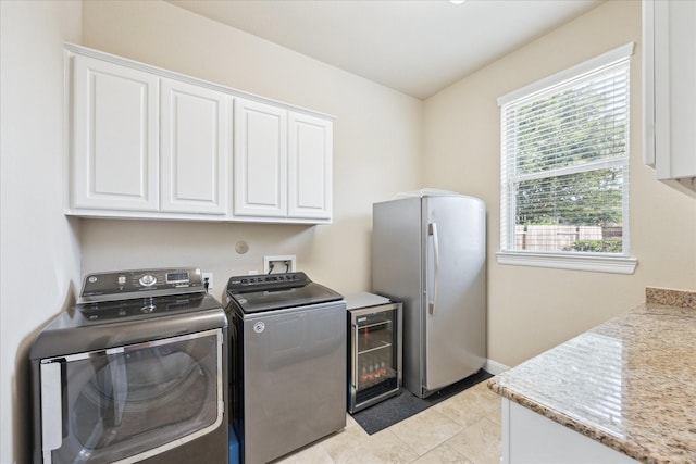washroom featuring washing machine and clothes dryer, light tile patterned flooring, cabinet space, beverage cooler, and baseboards