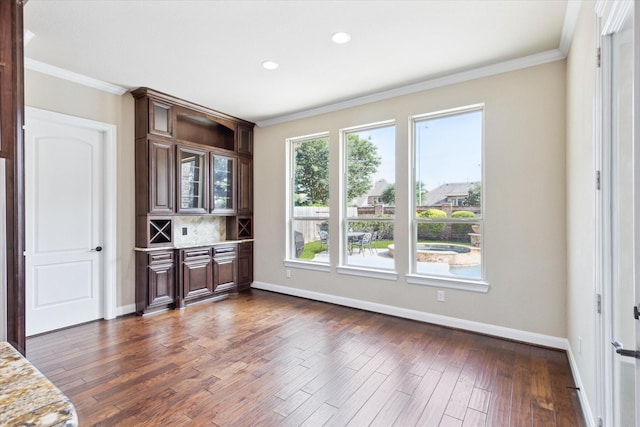 interior space with baseboards, dark wood-type flooring, and crown molding