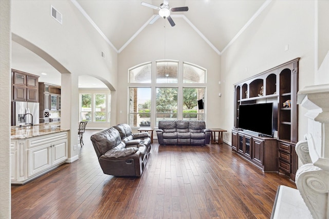 living area featuring visible vents, ceiling fan, dark wood-style floors, high vaulted ceiling, and arched walkways