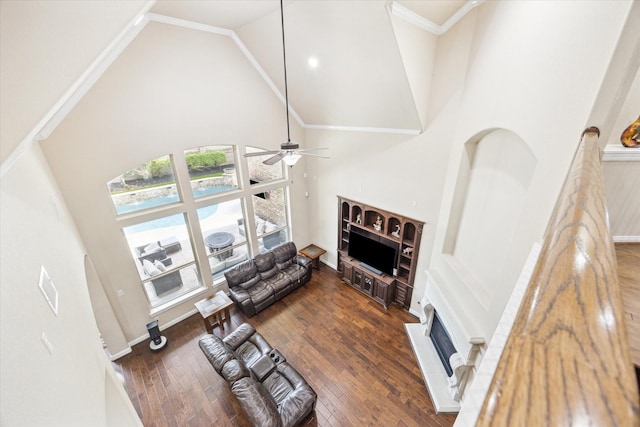 living area featuring high vaulted ceiling, ceiling fan, a fireplace with raised hearth, and wood finished floors