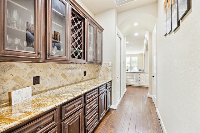 bar with decorative backsplash, baseboards, recessed lighting, hardwood / wood-style flooring, and arched walkways