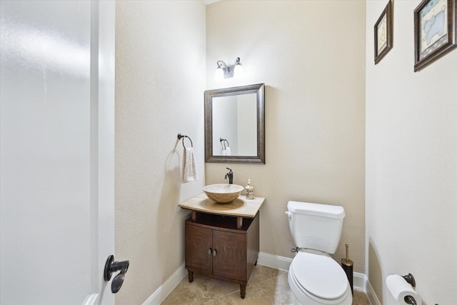 half bathroom featuring vanity, baseboards, tile patterned floors, and toilet