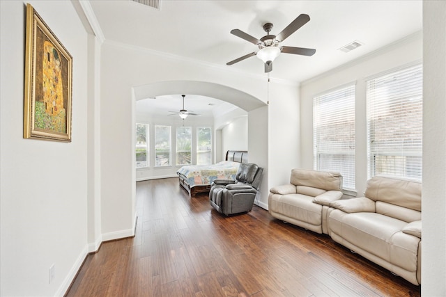 living room with crown molding, baseboards, ceiling fan, arched walkways, and dark wood finished floors