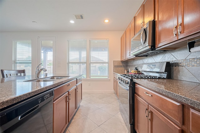 kitchen featuring brown cabinetry, a sink, appliances with stainless steel finishes, and a wealth of natural light