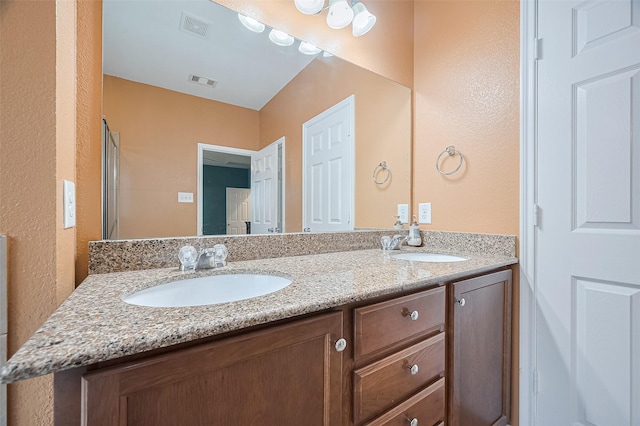 full bathroom with visible vents, a sink, and a textured wall