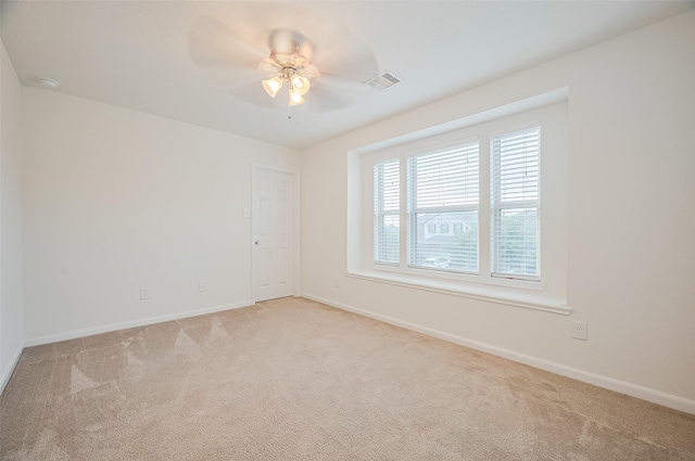 spare room featuring a ceiling fan, baseboards, visible vents, and light carpet
