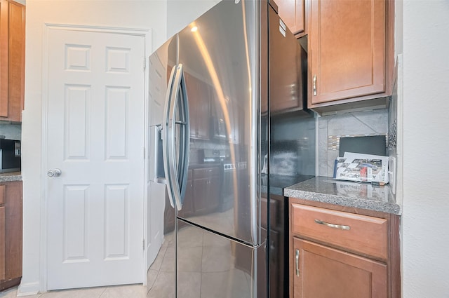 kitchen with tasteful backsplash, light tile patterned floors, brown cabinets, and stainless steel fridge with ice dispenser