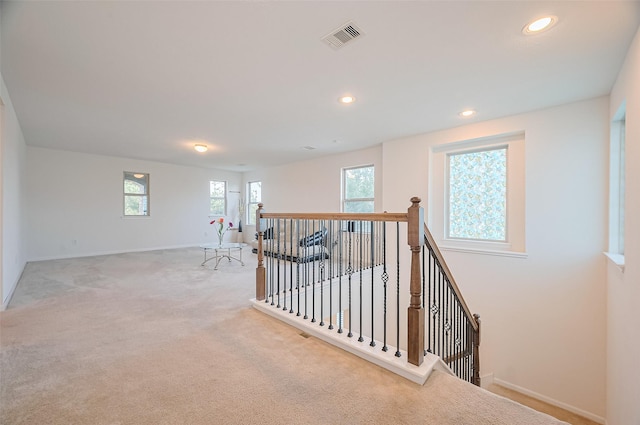 interior space featuring baseboards, visible vents, carpet flooring, and an upstairs landing