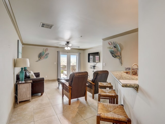 living room with visible vents, ornamental molding, baseboards, a ceiling fan, and light tile patterned floors