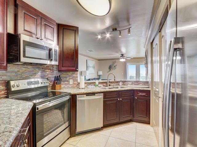 kitchen with light tile patterned flooring, a sink, stainless steel appliances, a ceiling fan, and decorative backsplash
