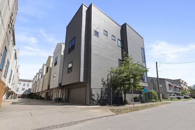 view of side of home with an attached garage, central air condition unit, and a residential view
