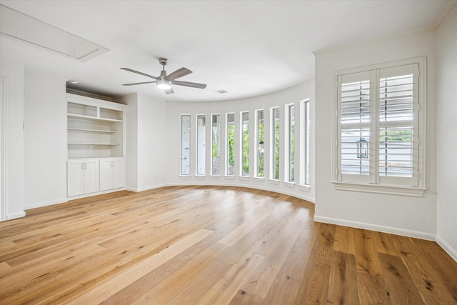 unfurnished living room featuring baseboards, ceiling fan, light wood-style floors, and attic access