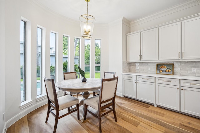 dining area with an inviting chandelier, plenty of natural light, crown molding, and light wood-type flooring