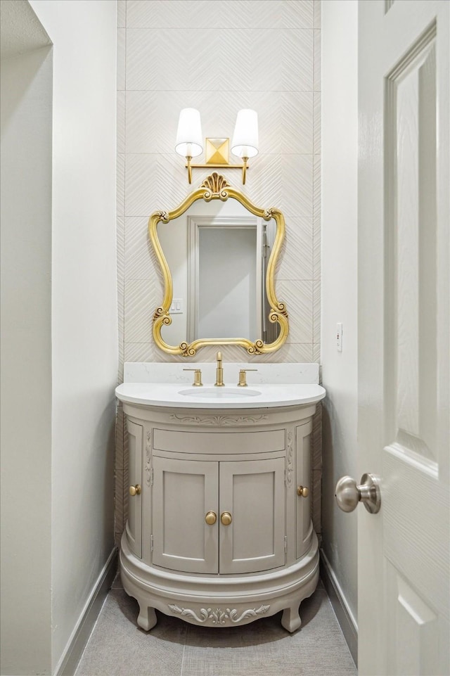 bathroom with wallpapered walls, baseboards, and vanity