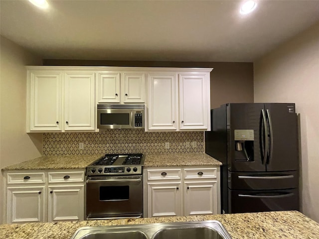 1718 Elgin St, Houston, TX 77004 - kitchen with appliances with stainless steel finishes, decorative backsplash, white cabinets, and light stone counters