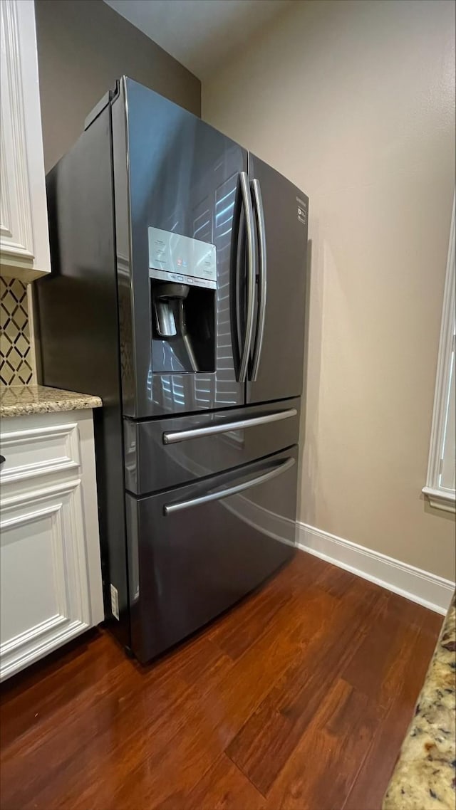 1718 Elgin St, Houston, TX 77004 - kitchen featuring stainless steel fridge, dark wood finished floors, white cabinetry, baseboards, and light stone counters