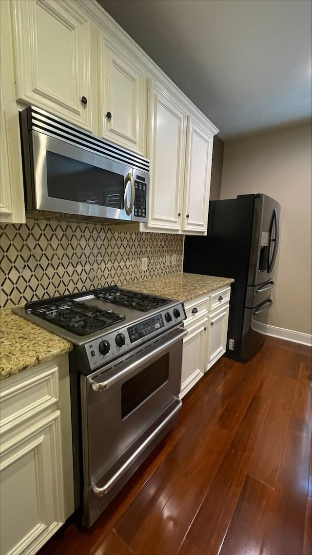 1718 Elgin St, Houston, TX 77004 - kitchen with appliances with stainless steel finishes, dark wood-style floors, tasteful backsplash, baseboards, and light stone counters