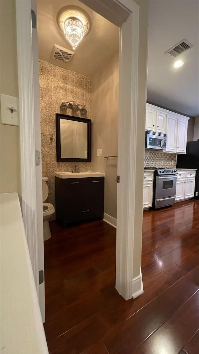 1718 Elgin St, Houston, TX 77004 - bathroom featuring hardwood / wood-style flooring, toilet, backsplash, a chandelier, and vanity