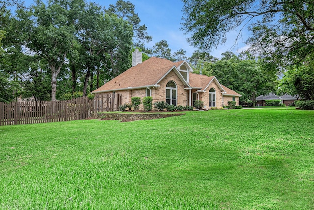 view of front of house with brick siding, fence, a chimney, and a front lawn