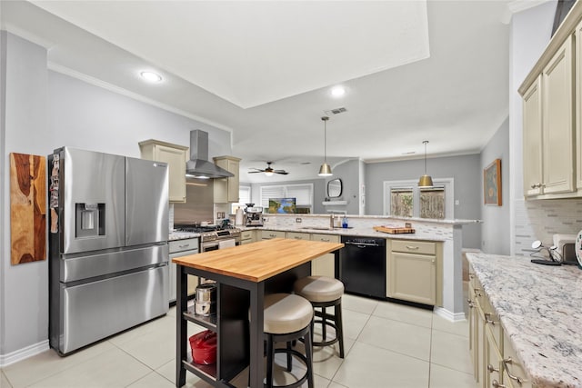 20415 Aspenwilde Dr, Cypress, TX 77433 - kitchen with decorative backsplash, appliances with stainless steel finishes, wall chimney exhaust hood, a peninsula, and butcher block countertops