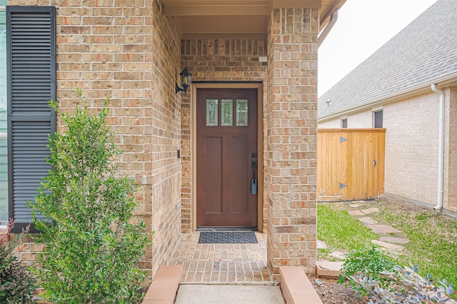 property entrance featuring a gate and brick siding