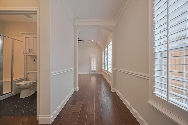 hall with arched walkways, baseboards, ornamental molding, and dark wood-style floors