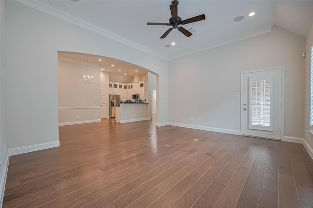unfurnished living room with dark wood-style flooring, arched walkways, ceiling fan with notable chandelier, baseboards, and ornamental molding