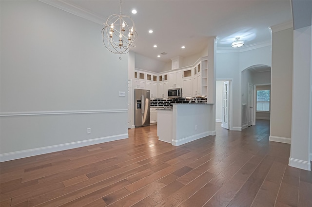 kitchen with crown molding, arched walkways, white cabinets, stainless steel appliances, and recessed lighting