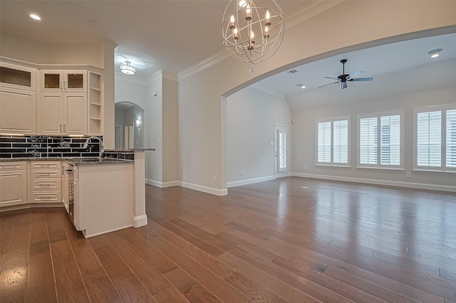kitchen featuring arched walkways, open shelves, ceiling fan with notable chandelier, open floor plan, and ornamental molding