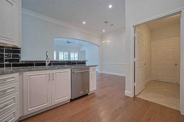 kitchen with stainless steel dishwasher, ornamental molding, arched walkways, and white cabinets