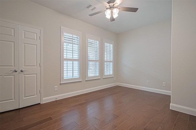 spare room with visible vents, a ceiling fan, baseboards, and dark wood-style flooring