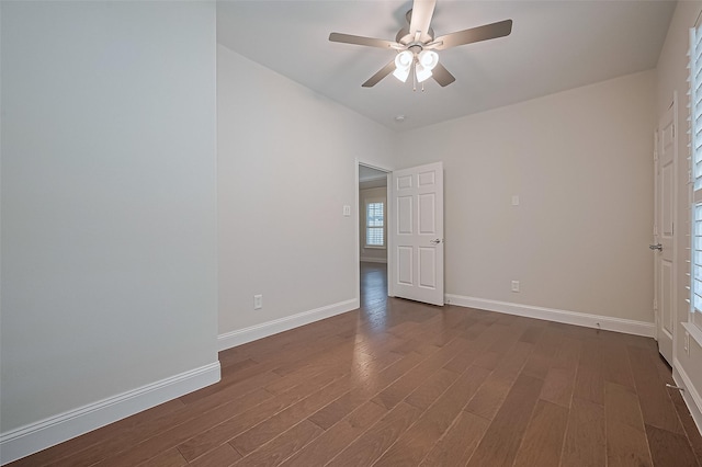 spare room with baseboards, ceiling fan, and dark wood-type flooring